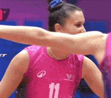 a woman in a pink tank top with the number 11 on it is hugging another woman