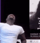 a man in a white t-shirt is dancing in front of a screen that says zoe