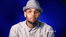 a man wearing a hat and glasses is looking at the camera