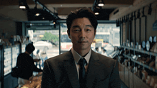 a man in a suit and tie stands in front of a window in a store