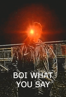 a man is standing in front of a building with a red light shining on his face and the words boi what you say below him .