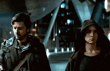 a man and a woman are walking in a dark room
