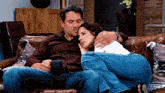 a man and a woman are sitting on a couch with a cup of coffee