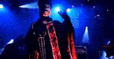 a man in a cape stands in front of a blue light