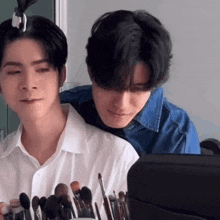 two men are standing next to each other with makeup brushes