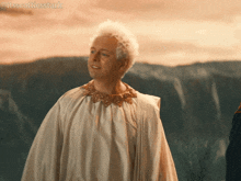 a man in a white robe is standing in front of a mountain