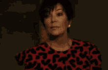a woman is wearing a red and black leopard print dress and earrings .