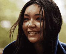 a woman wrapped in a blue blanket is smiling with her hair blowing in the wind