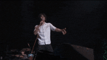 a man wearing a white shirt that says ' nirvana ' on it is holding a microphone