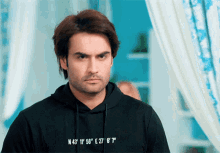 a man wearing a black hoodie that says n 43 ' 11 ' 56 ' e 27 ' 6 "