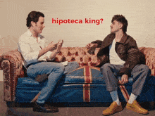 two men are sitting on a couch with the word hipoteca king written above them
