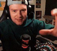 a man wearing headphones and a green sweatshirt is giving a thumbs up .