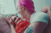 a woman with pink hair kisses another woman on the forehead