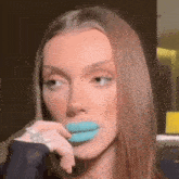 a close up of a woman 's face with blue lipstick in her mouth .