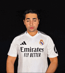 a man wearing a emirates fly better shirt holds up his hand