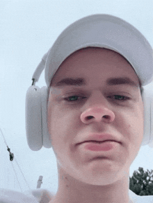 a young man wearing headphones and a hat is making a face
