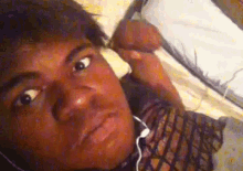 a man wearing headphones is laying on a bed looking at the camera .
