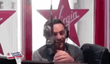 a man wearing headphones is sitting at a table in front of a microphone in a radio station .