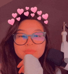 a girl wearing glasses and a crown of pink hearts on her head