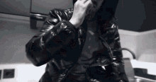 a man in a black jacket is smoking a cigarette in a kitchen