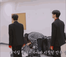 a group of people are standing in a room with korean writing on the bottom of the screen