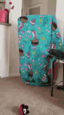 a turquoise blanket with a pattern of dolls on it