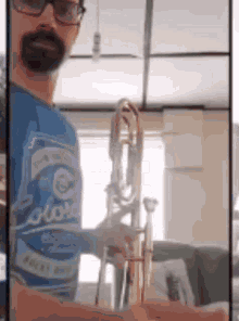 a man in a blue shirt is holding a trombone in his hands .