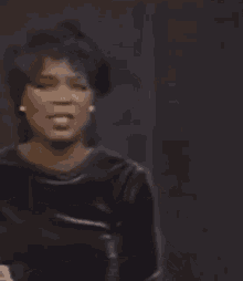 a woman is singing into a microphone while wearing a black dress .