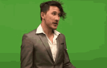 a man in a suit and white shirt on a green screen .
