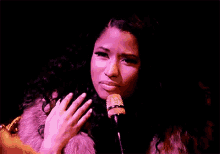 a woman in a pink fur coat is singing into a microphone .