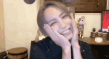 a woman is smiling with her hands on her face in front of a computer screen