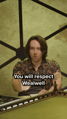 a man sitting at a table with the words " you will respect wealwell " on the bottom