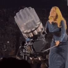 a woman in a blue dress is standing in front of a machine that looks like a missile
