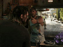 a man wearing a tank top that says conda talks to another man in front of an exit sign