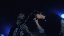 a man singing into a microphone while another man holds a guitar