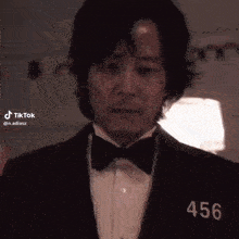 a man in a tuxedo and bow tie with the number 456 on his shirt .