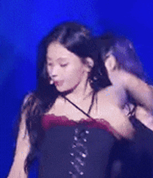 a woman in a corset is dancing on a stage with a blue background .