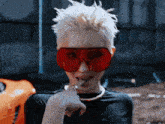 a woman wearing a black shirt and red sunglasses smoking a cigarette