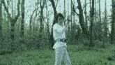 a man in a white shirt and white pants is standing in a field