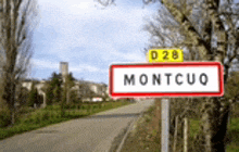 a red and white sign on the side of a road that says montcuq