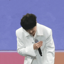 a man in a white jacket holds a microphone in his hand