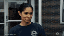 a woman wearing a chicago fire department shirt stands in front of a building