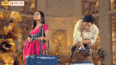 a woman in a pink dress is standing next to a man with a suitcase in front of a star plus sign