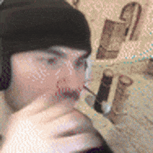 a man wearing headphones and a beanie is drinking from a bottle of wine .