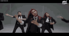a group of women in suits and ties are dancing in front of a sign that says the k