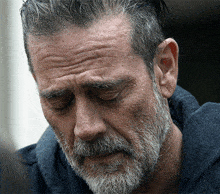 a man with a beard and gray hair looks down