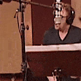 a man wearing headphones and a black shirt is speaking into a microphone