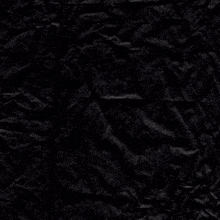 a piece of crumpled black paper with a purple flower in the middle
