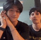 two young men are sitting next to each other and one of them is wearing a bracelet .