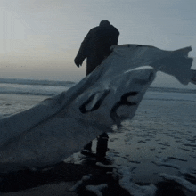 a person walking on a beach with a white cloth that says uc